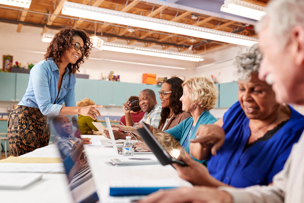 Seniors sitting at long table with tablets